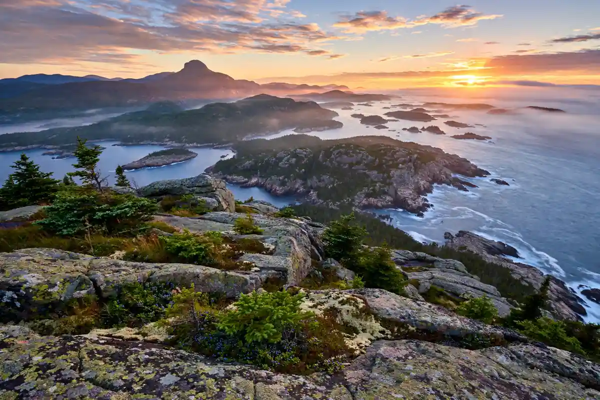 Rocky Maine coastline and Cadillac Mountain at sunrise in Acadia National Park