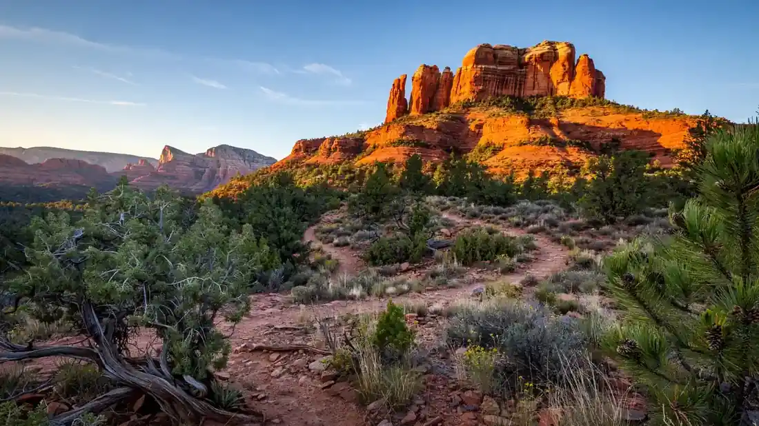 Cathedral Rock glowing at sunrise over a Sedona Arizona hiking trail