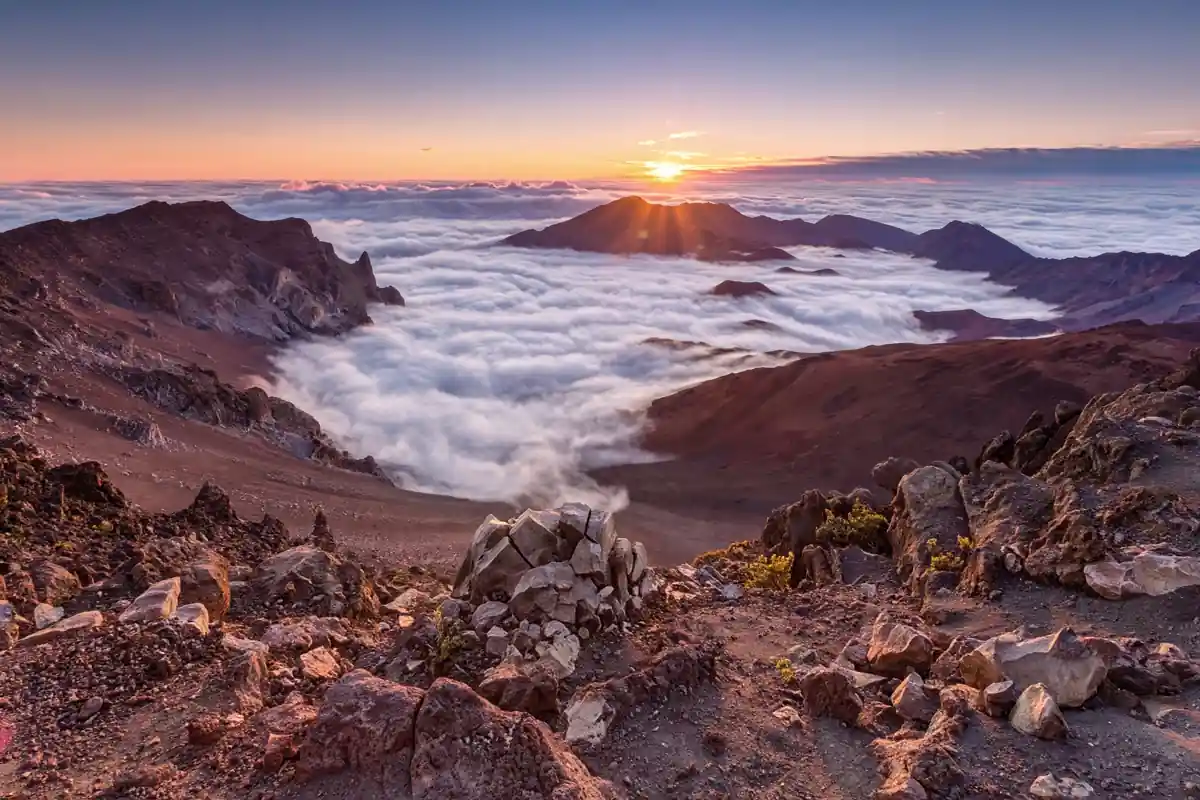Haleakala volcano crater at sunrise with a sea of clouds below the summit